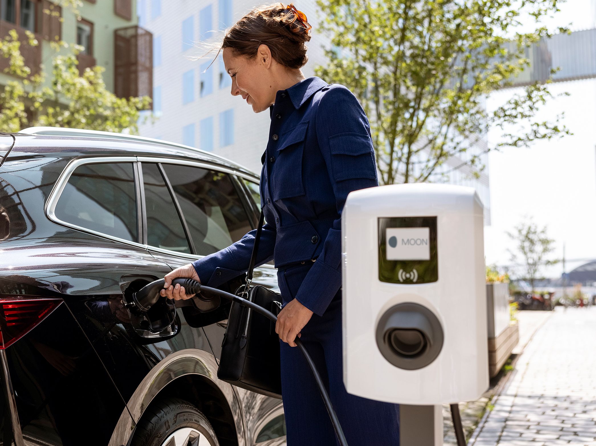 Nő csapszelepet helyez be egy autóba, ahol előtérben fali doboz van