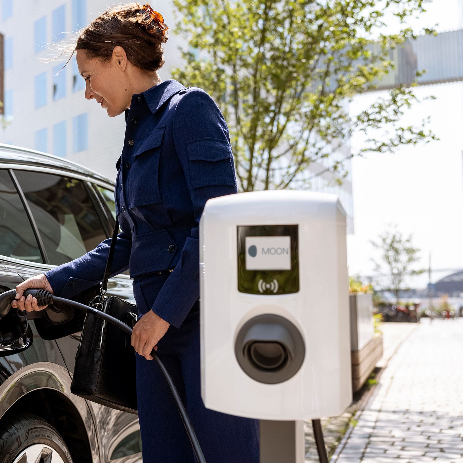 Nő csapszelepet helyez be egy autóba, ahol előtérben fali doboz van
