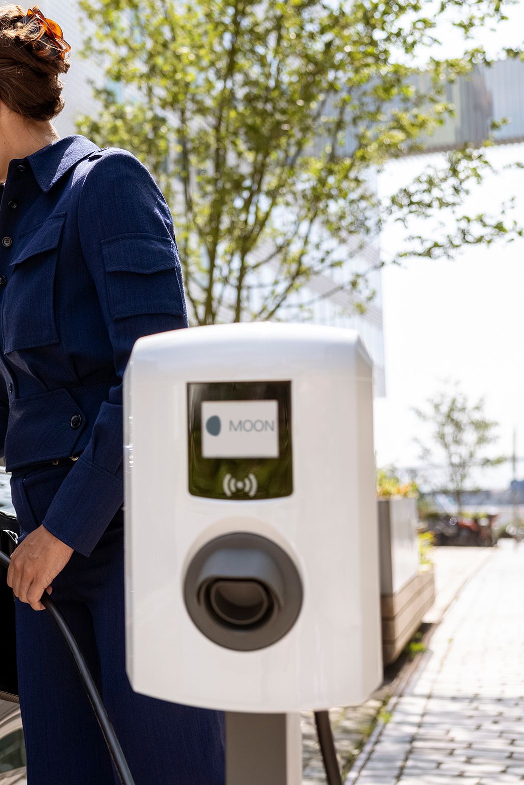 Nő csapszelepet helyez be egy autóba, ahol előtérben fali doboz van