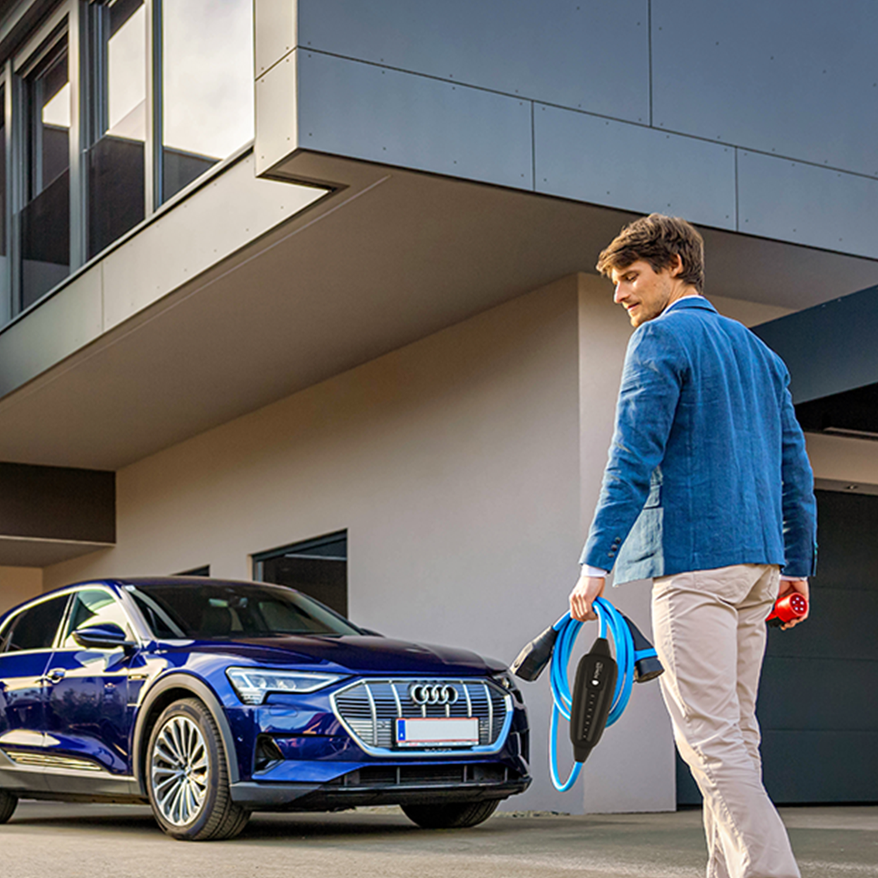 Az ember egy autó felé sétál kábellel a kezében