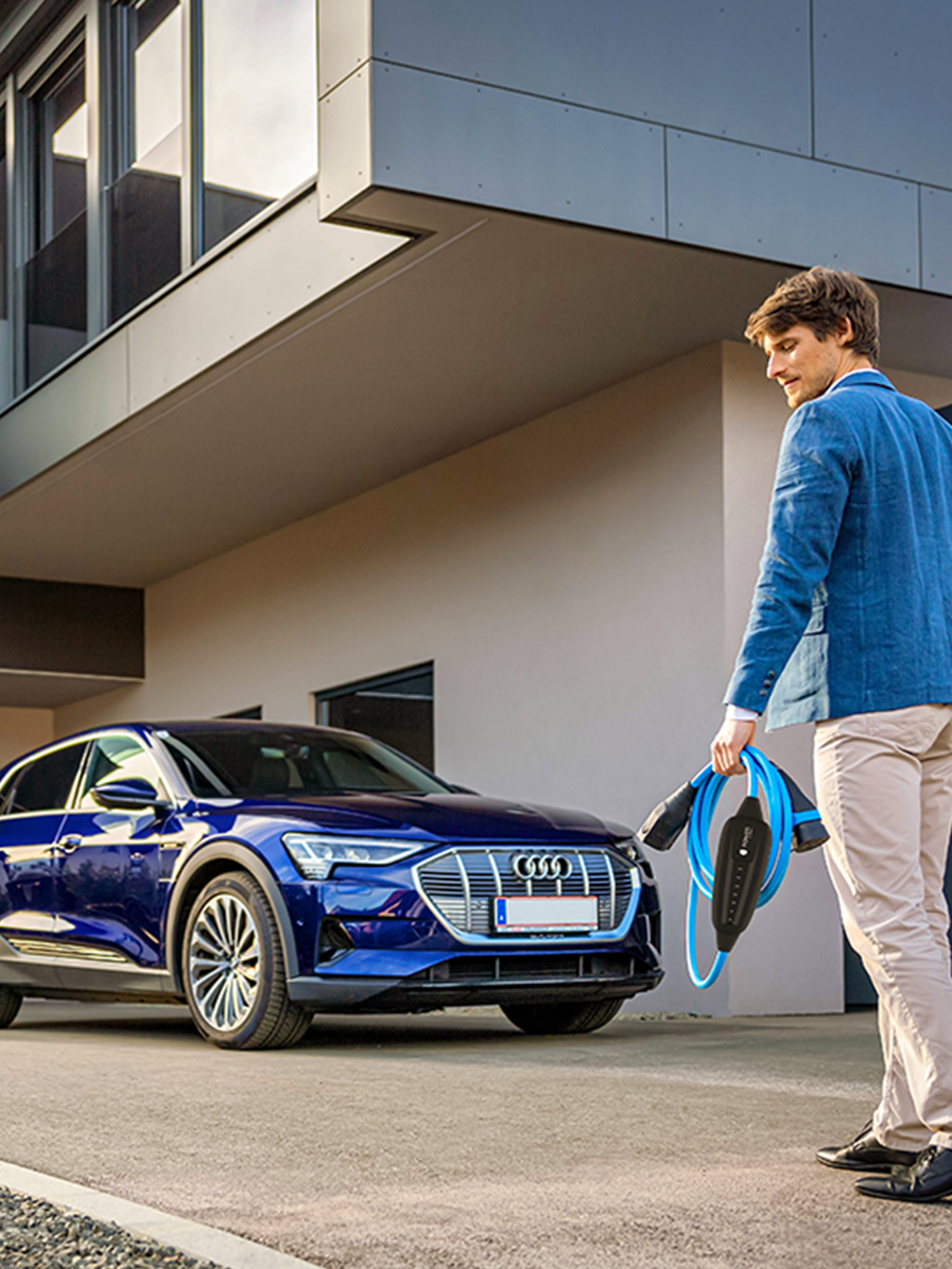 Az ember egy autó felé sétál kábellel a kezében