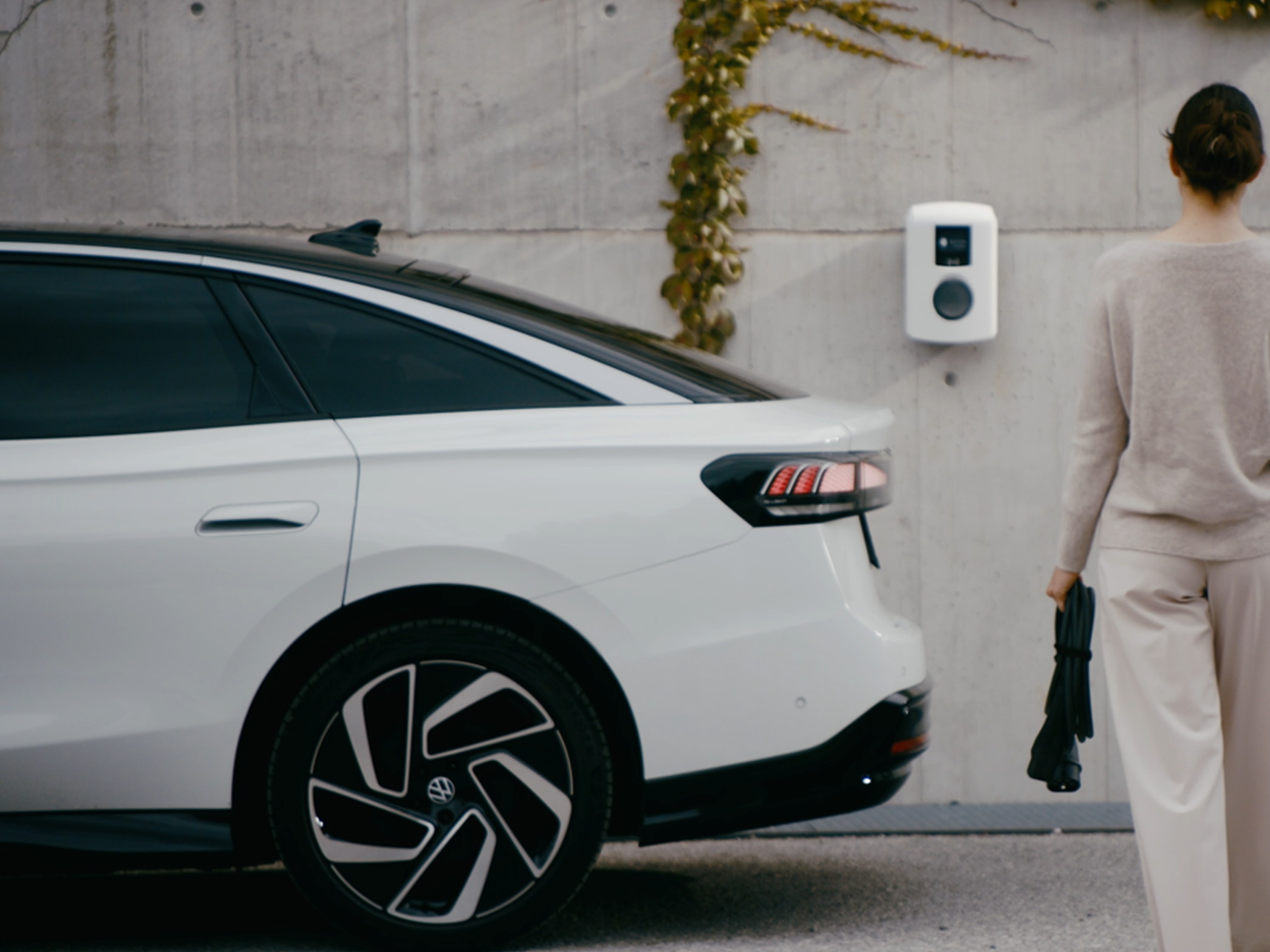 Egy nő egy falon lévő töltőállomás felé sétál