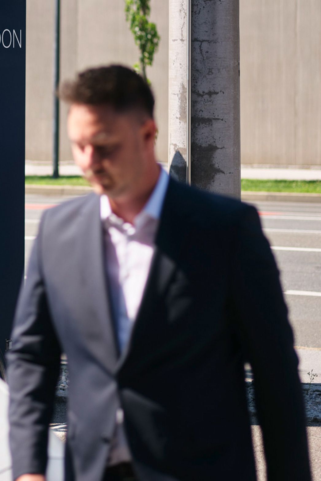 Egy férfi egy autó előtt sétál egy töltőállomás előtt