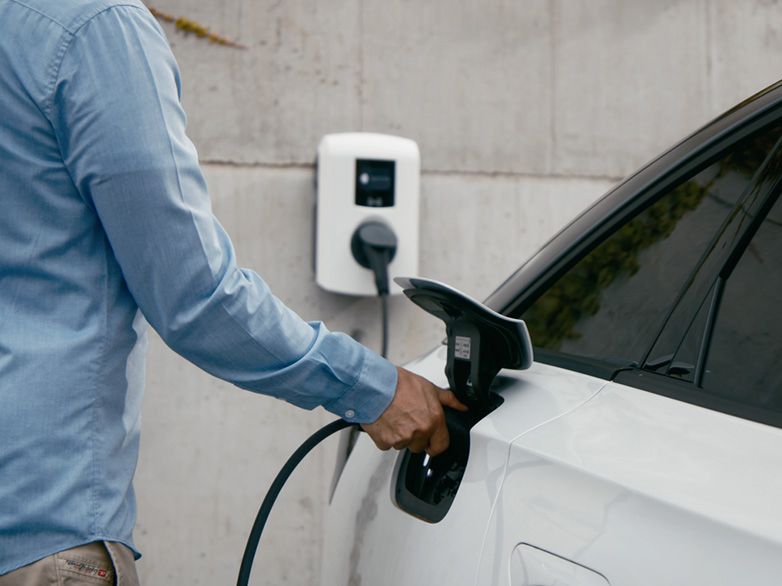 Valaki tölti az autót egy fali doboznál