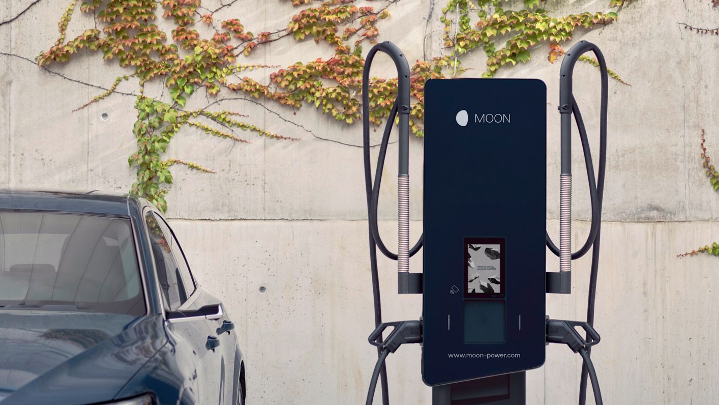 Az autó egy töltőállomás mellett parkol.