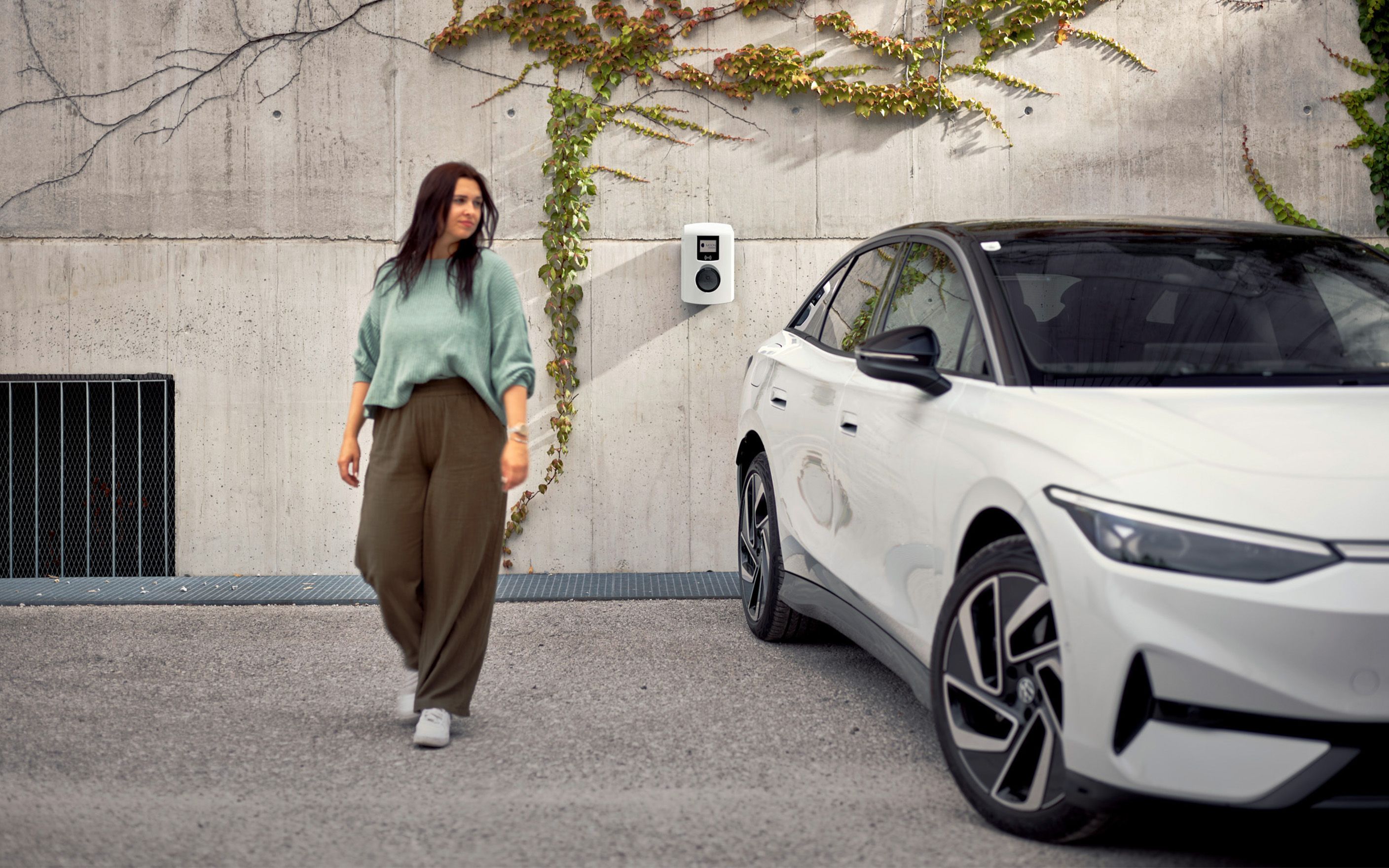 Nő egy fehér autó mellett sétál