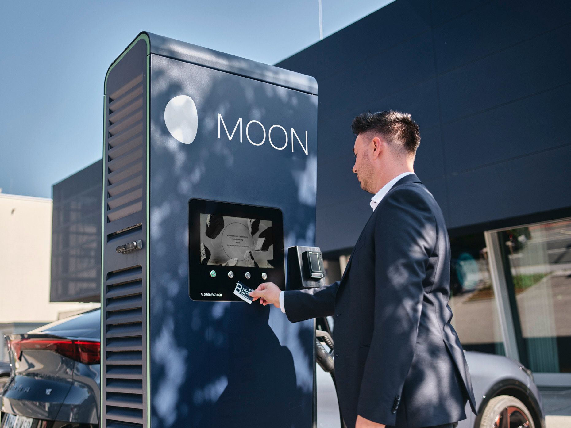 Az ember kártyát tart egy töltőállomáshoz