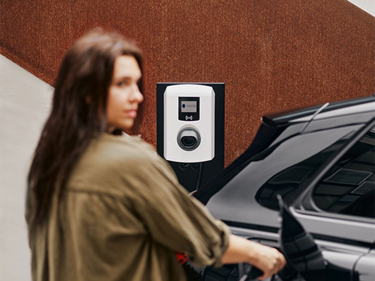 Nő egy fali dobozzal tölti az autót